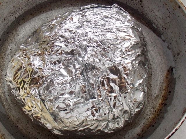 Положите завёрнутое в фольгу мясо в чугунную сковороду Положите завёрнутое в фольгу мясо в чугунную сковороду
