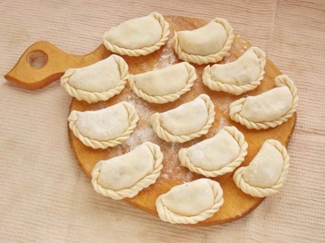 Выложите слепленные вареники с картошкой на доску и присыпьте мукой Выложите слепленные вареники с картошкой на доску и присыпьте мукой