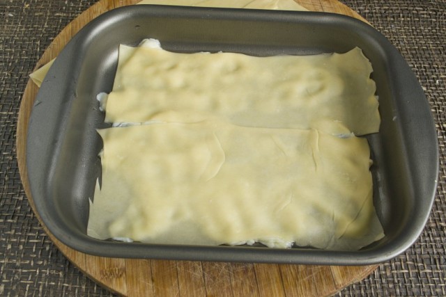 В форму для лазаньи выкладываем немного соуса и накрываем листами пасты