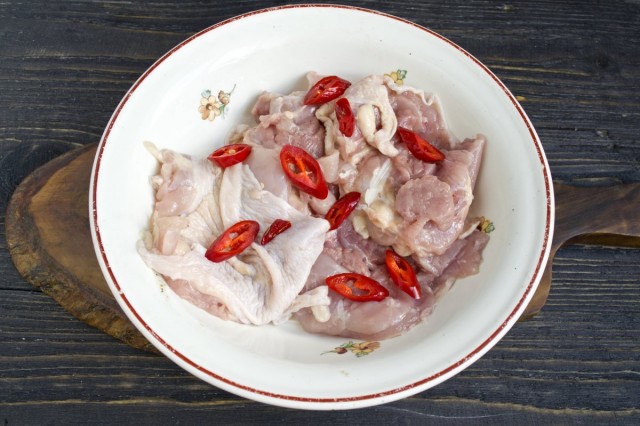 Перекладываем мясо курицы в миску, нарезаем острый или сладкий перец по вкусу