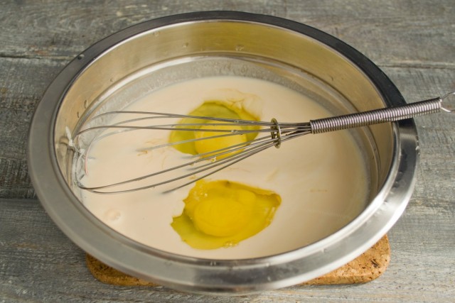 Наливаем оливковое масло и ряженку, насыпаем щепотку соли, разбиваем яйца