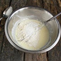 Насыпаем просеянную с разрыхлителем и содой пшеничную муку, солим и замешиваем тесто