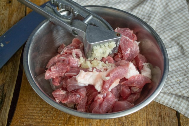 Кладём нарезанное мясо в миску, добавляем чеснок
