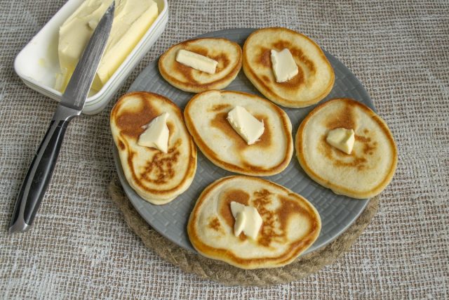 На каждый горячий оладушек кладём небольшой кусочек сливочного масла На каждый горячий оладушек кладём небольшой кусочек сливочного масла