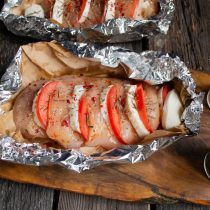 Посыпаем курицу хлопьями копченой паприки и ароматными травами, закручиваем сначала края пергамента, а затем фольгу Посыпаем курицу хлопьями копченой паприки и ароматными травами, закручиваем сначала края пергамента, а затем фольгу
