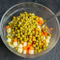 Остывшие овощи кладём в салатник, добавляем консервированный зелёный горошек
