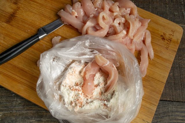 Кладём нарезанное мясо в пакет с панировкой, завязываем и встряхиваем Кладём нарезанное мясо в пакет с панировкой, завязываем и встряхиваем