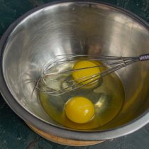 Разбиваем в миску куриные яйца, добавляем сахар и соль, взбиваем венчиком 