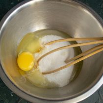 Разбиваем в миску куриные яйца, добавляем сахарный песок и щепотку мелкой соли