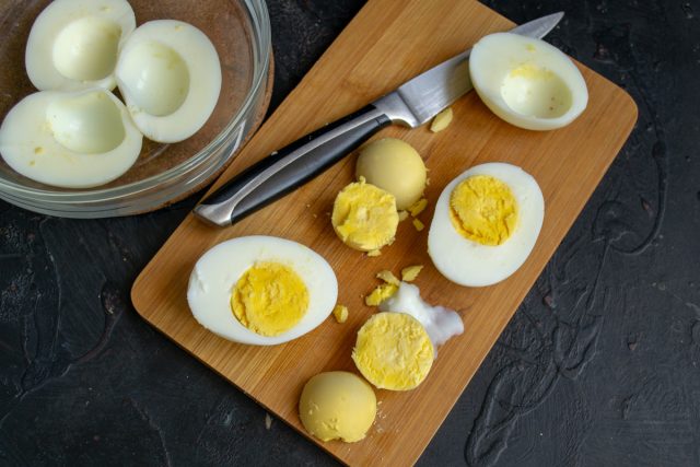 Разрезаем варёные яйца вдоль пополам, достаём желтки