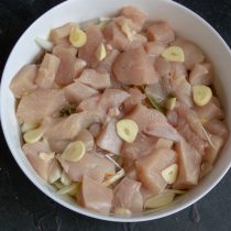 Выкладываем нарезанное кубиками куриное филе и пластинки чеснока Выкладываем нарезанное кубиками куриное филе и пластинки чеснока