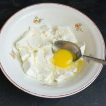 К творогу добавляем куриное яйцо, соль и сахарный песок