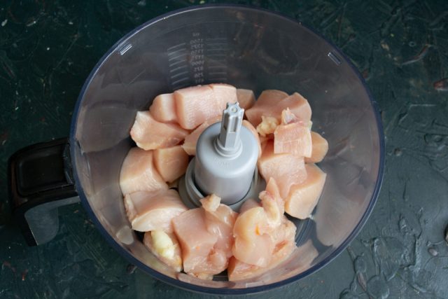 В чашу кухонного комбайна кладём нарезанное кубиками филе