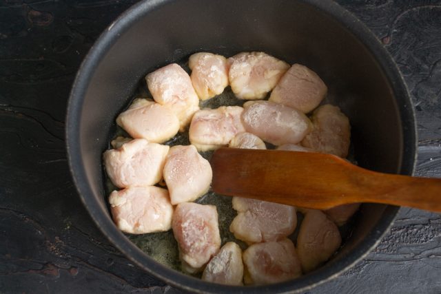 В кастрюлю наливаем растительное масло, кладём кусочки куриного филе и обжариваем 
