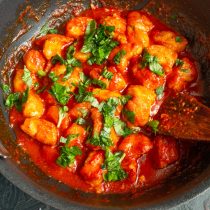 Нагреваем курицу с томатным соусом до кипения, готовим 10 минут, добавляем нарезанный зелёный базилик и перемешиваем