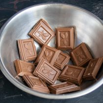 Ломаем на кусочки плитки молочного шоколада, кладём в миску Ломаем на кусочки плитки молочного шоколада, кладём в миску