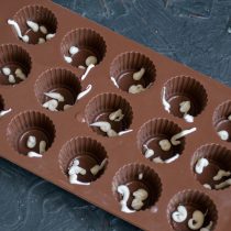 На дно и бока силиконовой формы для конфет капаем белым шоколадом