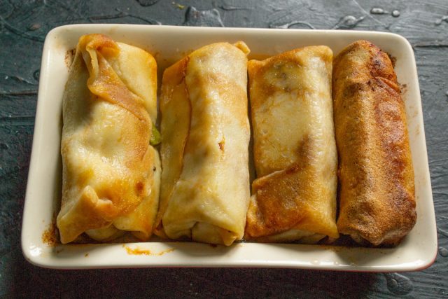 Кладём на фаршированные блины кусочки сливочного масла и отправляем блюдо в духовой шкаф Кладём на фаршированные блины кусочки сливочного масла и отправляем блюдо в духовой шкаф