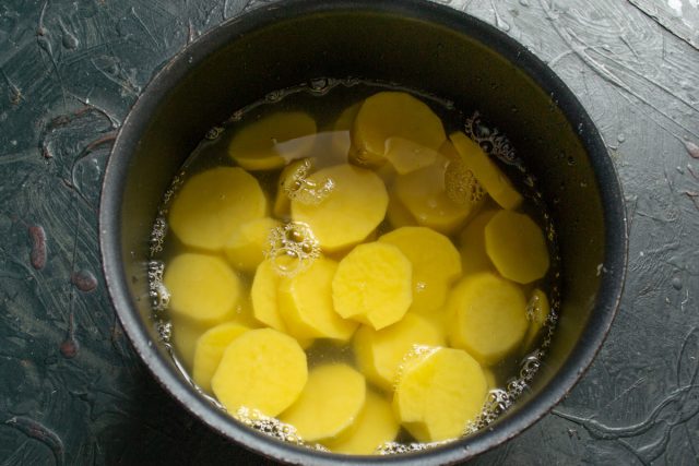 Картофель чистим, нарезаем толстыми ломтиками. Кладём очищенный картофель в кастрюлю, заливаем горячей водой