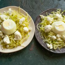 Выкладываем на тарелку салат из редьки, сверху крошим творог и кладем по яйцу-пашот