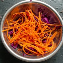 Сырую, нарезанную узкими полосками морковку добавляем к капусте