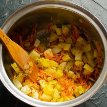 Бросаем нарезанную картошку в кастрюлю и обжариваем вместе с овощами