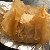Сначала плотно заворачиваем кусок мяса в бумагу для выпечки