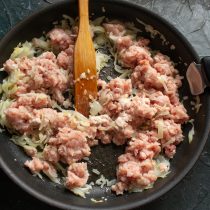 Добавляем к луку мясной фарш. Разминаем кусочки фарша лопаткой Добавляем к луку мясной фарш. Разминаем кусочки фарша лопаткой