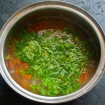 Петрушку и редисочную ботву режем мелко, бросаем в кипящий суп