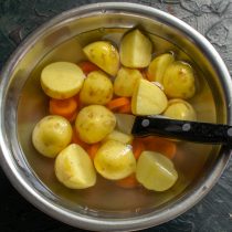 Очищенный картофель разрезаем пополам. Морковь нарезаем толстыми кружочками