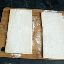 Слоёное дрожжевое тесто достаём из морозильной камеры. Посыпаем доску мукой, кладём листы теста, прикрываем пищевой плёнкой Слоёное дрожжевое тесто достаём из морозильной камеры. Посыпаем доску мукой, кладём листы теста, прикрываем пищевой плёнкой