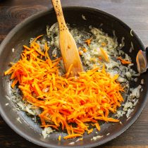 Обжариваем лук, пока не испарится бульон. Затем кладём тёртую морковь и обжариваем овощи ещё 5 минут