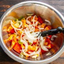 Сладкую салатную луковицу режем тонкими полукольцами. Нарезанный лук добавляем к перцу и помидорам