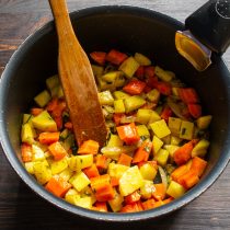 Следом за морковью добавляем нарезанный кубиками картофель. Обжариваем овощи 