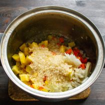 В суповую кастрюлю кладем нарезанные овощи: лук, морковь, картофель. Насыпаем рис