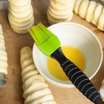 Разбиваем куриное яйцо в миску, смазываем тесто яйцом.