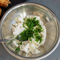 Выкладываем рикотту в миску, добавляем чеснок и нарезанную зелень.