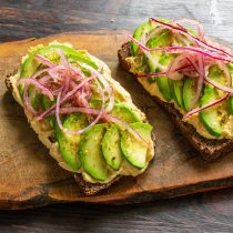 Выкладываем лук на авокадо, выливаем сверху масло с уксусом.