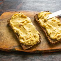 Намазываем хумус на хлеб, из расчета по 30 г на порцию.