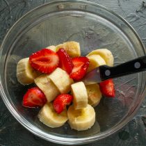 Один банан и половину клубники нарезаем мелко, кладём в миску.
