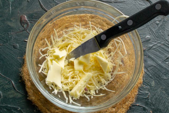 Нарезаем кубиками размягченное сливочное масло, добавляем к сыру и чесноку.