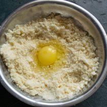 Делаем углубление в масляной крошке, разбиваем крупное куриное яйцо