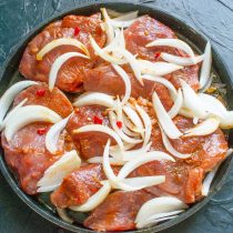 Выкладываем на мясо лук и чили