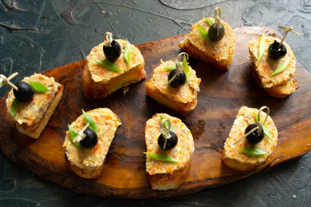 На остывшую гренку кладём ломтик паштета, сверху прикрепляем оливку с помощью коктейльной шпажки