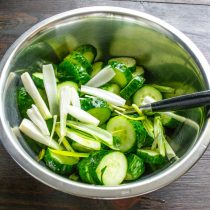 Белую часть зеленого лука режем соломкой, добавляем к огурцам.