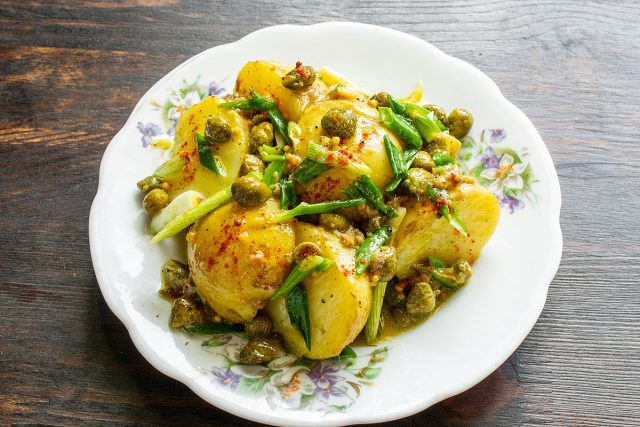Выкладываем салат из молодого картофеля с анчоусами и каперсами на тарелку горкой.