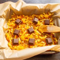 На ровный пласт из апельсиновых цукатов выкладываем кусочки молочного шоколада. На ровный пласт из апельсиновых цукатов выкладываем кусочки молочного шоколада.
