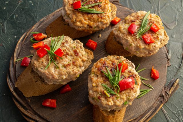 Выкладываем котлеты на ломтики ржаного хлеба, посыпаем кубиками красного болгарского перца, украшаем розмарином и сразу подаём на стол.