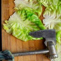 Остужаем капустные листья на доске, молоточком для мяса отбиваем плотную часть.