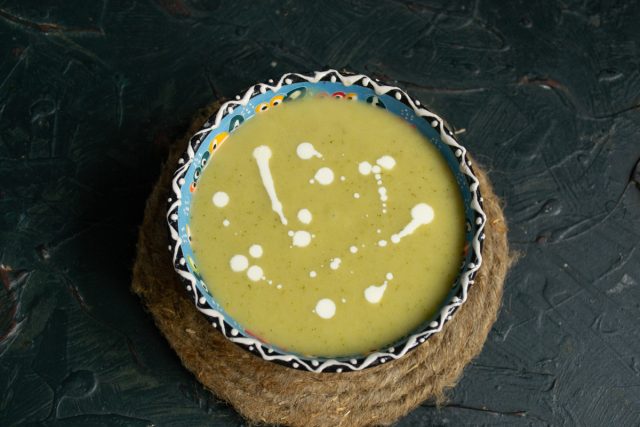 Разливаем горячий сливочный овощной суп, приготовленный на курином бульоне в тарелки, поливаем сливками.